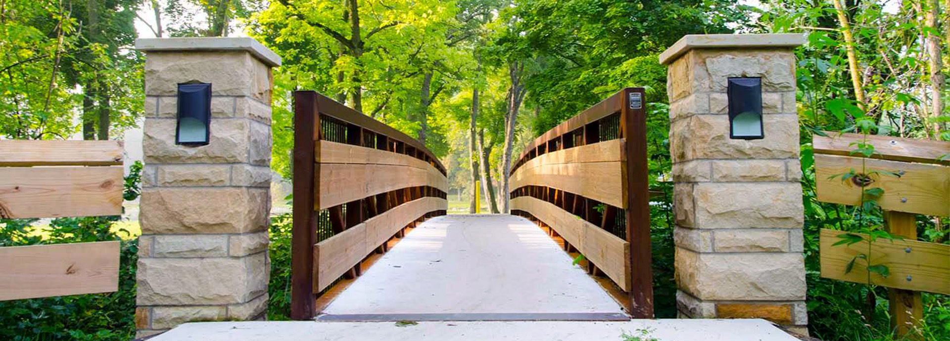 Slideshow Image - A rustic wooden bridge surrounded by lush greenery