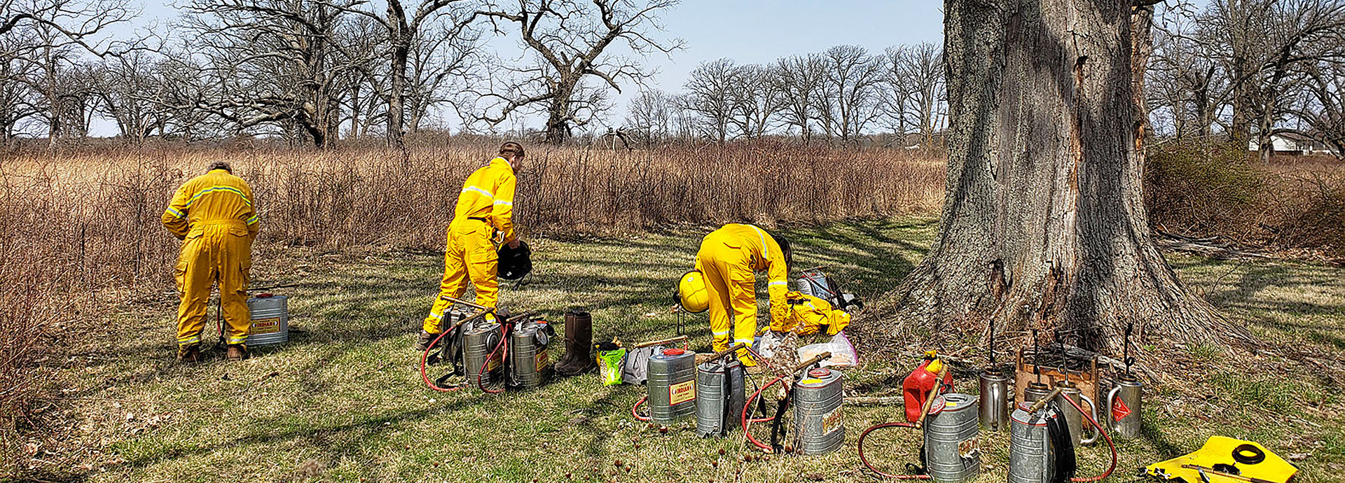 Slideshow Image - Several staff members setting up to perform a controlled burn on a dry prairie